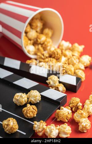 Sweet caramel popcorn and clapper board on red background Stock Photo
