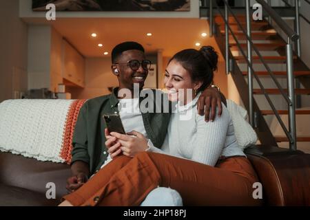 Biracial couple sitting on sofa texting on the phone Stock Photo