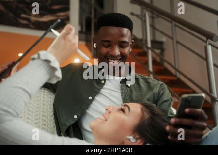 Biracial couple relaxing together on couch while using technology  Stock Photo