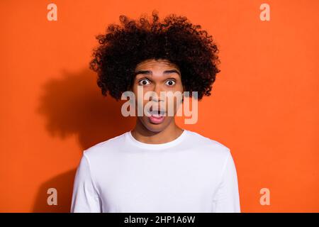 Photo of young astonished man crazy fake information open mouth isolated over orange color background Stock Photo