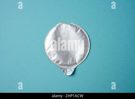 aluminum round lid from under the package with chips on a blue background, flat lay Stock Photo
