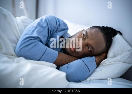 Young Man Suffering From Insomnia Lying In His Bed Stock Photo