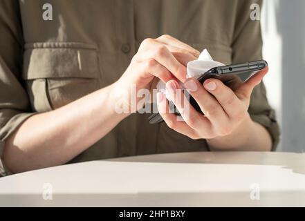 Woman hands closeup wiping phone screen. Gadget cleaning and personal hygiene concept. High quality photo Stock Photo