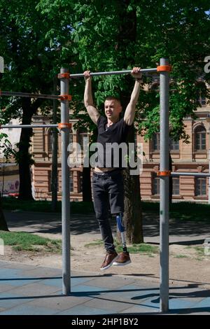 athletic young man with artificial leg working out on a bars Stock Photo
