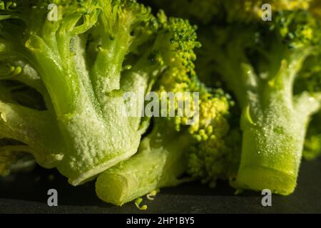 Frozen green broccoli florets on dark background closup Stock Photo