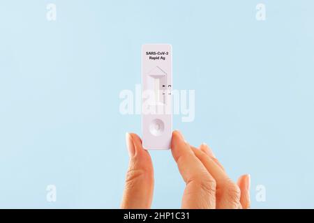 Woman holding COVID-19 coronavirus antigen rapid test over blue background. Selftesting at home. Stock Photo
