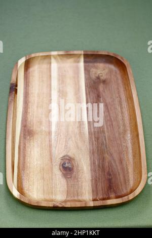 Close-up of a hardwood beige and brown rectangle serving tray with a rail or lip raised edge. Vertical acacia wooden rectangle tray that is used to se Stock Photo