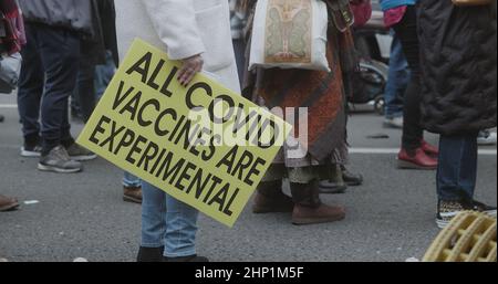 London, UK - 01 22 2022:  Protester holding a sign, ‘All Covid Vaccines Are Experimental’, at Portland Place from Regent park, in support of NHS100K. Stock Photo
