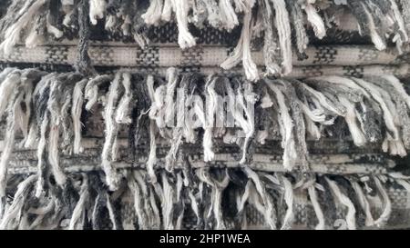 Woolen knitted clothing background. A stack of gray plaid wool blankets. Autumn, winter concept of home warmth and comfort. A bundle of neatly folded Stock Photo