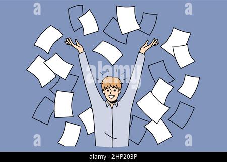Time management success and development concept. Smiling positive man worker standing in heap of flying papers documents with raised hands feeling exc Stock Photo