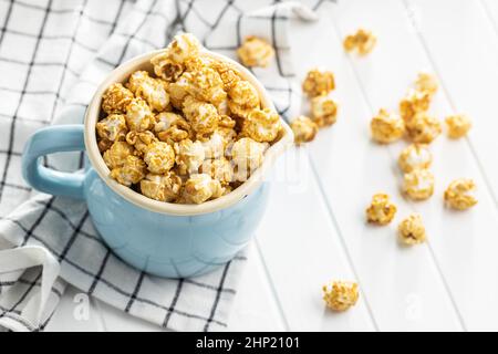 Sweet caramel popcorn in cup on white table. Stock Photo