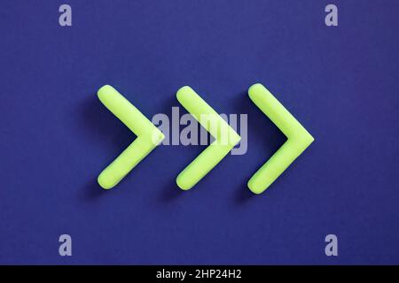 Green arrows pointing right side. Three dimensional arrow sign showing direction on blue background. Development  concept, go green or heading target Stock Photo