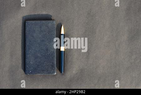 Pen placed on notebook on black background. High angle view. Copy space room for text. Stock Photo