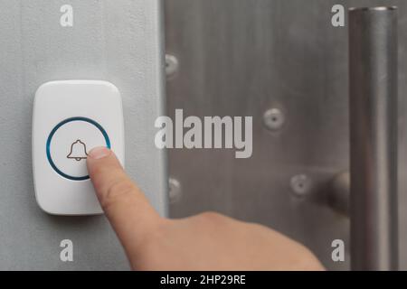 Hand pressing button on outdoor doorbell with an intercom. Stock Photo