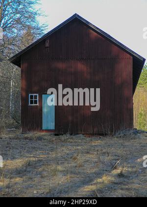 Old wooden door and small window on side of a red barn. Stock Photo