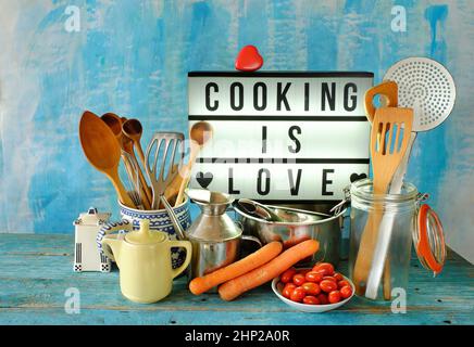 various vintage kitchen utensils and sign with "cooking is love" message Stock Photo