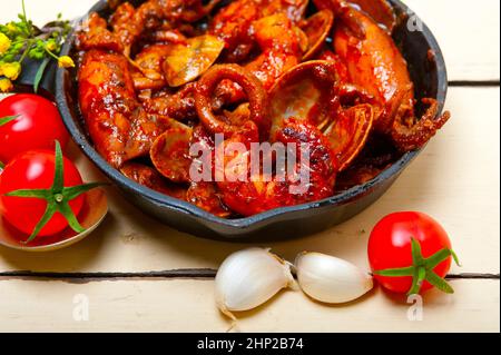fresh seafood stew prepared on an iron skillet ove white rustic wood table Stock Photo