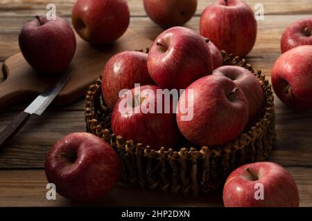 A lot of apples in a wooden basket placed in the wooden background. Stock Photo