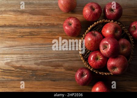 A lot of apples in a wooden basket placed in the wooden background. Stock Photo
