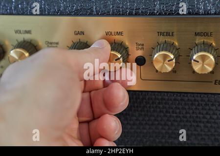 Cable plugged in to a guitar amplifier, adjusting gain and volume Stock Photo