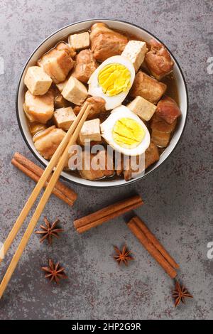 Kai palo Thai home style recipe for pork and egg stew spiced with cinnamon and star anise closeup in the bowl on the table. Vertical top view from abo Stock Photo