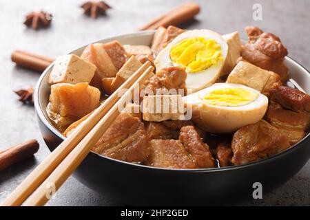 Kai Palo a Chinese influenced dish, is an amazingly fragrant Thai stew comprised of pork belly, tofu and eggs closeup in the bowl on the table. Horizo Stock Photo