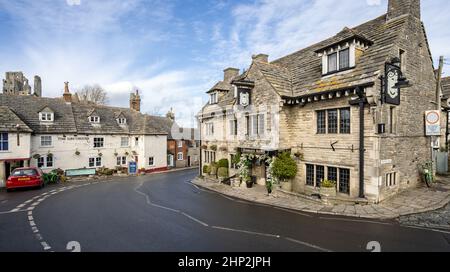The Bankes Arms and Greyhound Inn pubs with ruins of Corfe Castle in background, on East Street in Corfe, Dorset, UK on 18 February 2022 Stock Photo