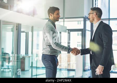Youve been doing exceptionally well. Shot of two businessmen shaking hands together in an office. Stock Photo