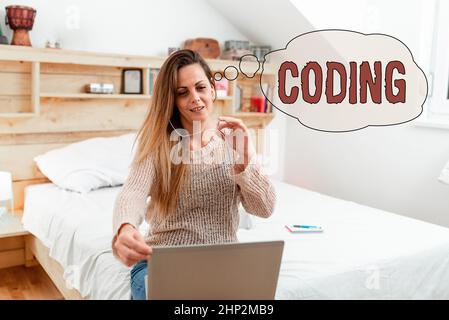 Text sign showing Coding, Business showcase assigning code to something for classification identification Woman vediocalling through laptop from bedro Stock Photo