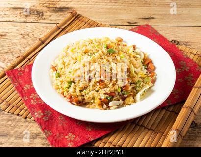 Char Siew Fried Rice in white plate on mat isolated on wooden background top view chinese rice Stock Photo