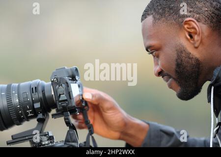 Side view portrait of a satisfied man with black skin checking photos on mirrorless camera Stock Photo