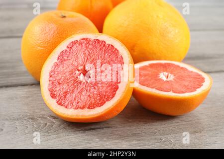 Pink grapefruit cut to half on wood desk, with whole citruses in background. Stock Photo