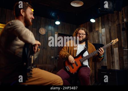Two young adult male friends playing electric guitars at studio. Improvised rock band. Music lesson Stock Photo