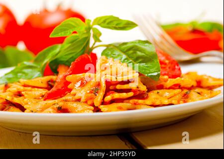 Italian pasta farfalle butterfly bow-tie with tomato basil sauce over white rustic wood table Stock Photo