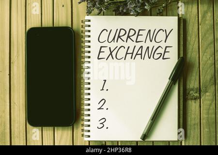Text sign showing Currency Exchange, Conceptual photo Process of changing one currency into another ForEx Empty Open Journal Beside Mobile With Pens O Stock Photo