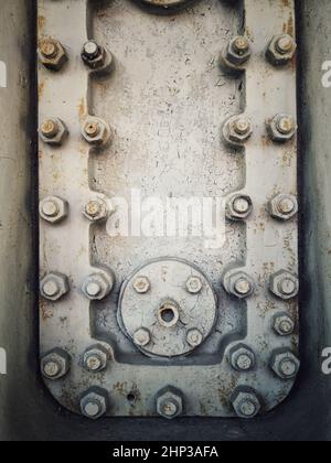 A grungy rusty steel hatch door secured with nuts and bolts. Stock Photo