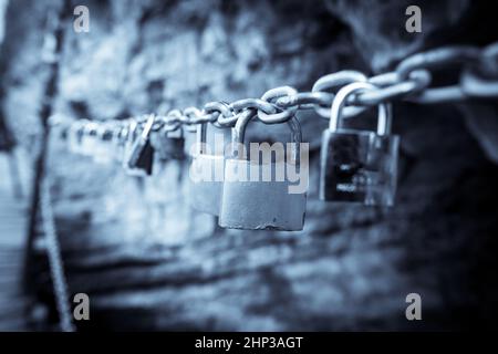 Close up shot of many padlocks on a chain, metaphor for a love relationship. Stock Photo