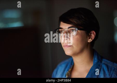 Working late to complete her assignment. Cropped shot of a young woman working late in her office. Stock Photo