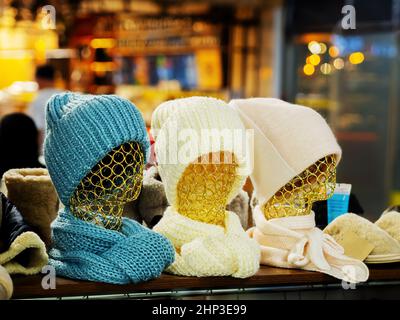 Three golden patterned women's mannequins in knitted winter hats and scarves in cozy shop. Selective focus Stock Photo
