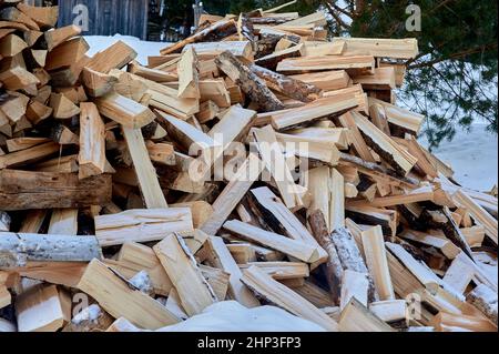 A pile of split firewood lies on the snow in winter. High quality photo Stock Photo