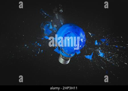 blue light bulb exploding on black. fragility concept. Stock Photo