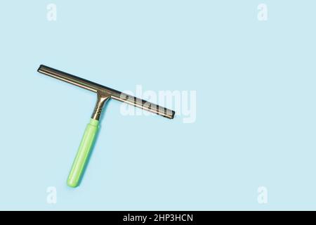 A hand held squeegee on a light blue background with copy space Stock Photo