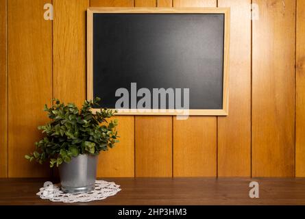 an empty blackboard hanging on a wooden wall Stock Photo