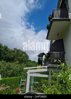 Man cleaning conservatory with a pressure washer - high pressure washer on patio glass surface Stock Photo