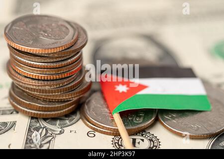 Stack of coins with Jordan flag on US dollar banknotes background. Stock Photo