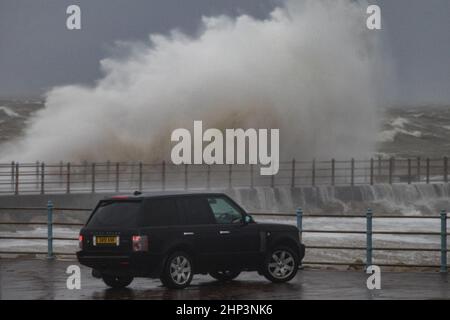 Morecambe Promenade, Morecambe Lancashire, United Kingdom. 18th Feb, 2022. Storm Eunice brought high winds to Morecambe with visitors to the seaside resort coming to take a close look Credit: PN News/Alamy Live News Stock Photo