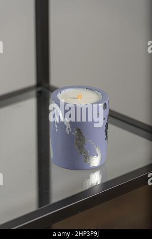 Round candle holder with abstract smudges, blue concrete with silver flame. selective soft focus Stock Photo
