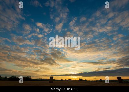 Altocumulus clouds give an attractive sunset over a field of harvested cereal crop in West Yorkshire Stock Photo