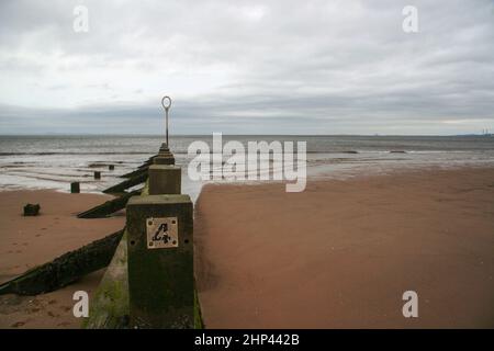 Old wooden groyne, with number 4 on it, overcast day, sea in background. Portobello beach, Edinburgh. Stock Photo