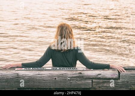 A young woman is swimming relaxed in a small pool, the blue background is  visible through the clear water illuminated by light, dark hair, burgundy  sw Stock Photo - Alamy